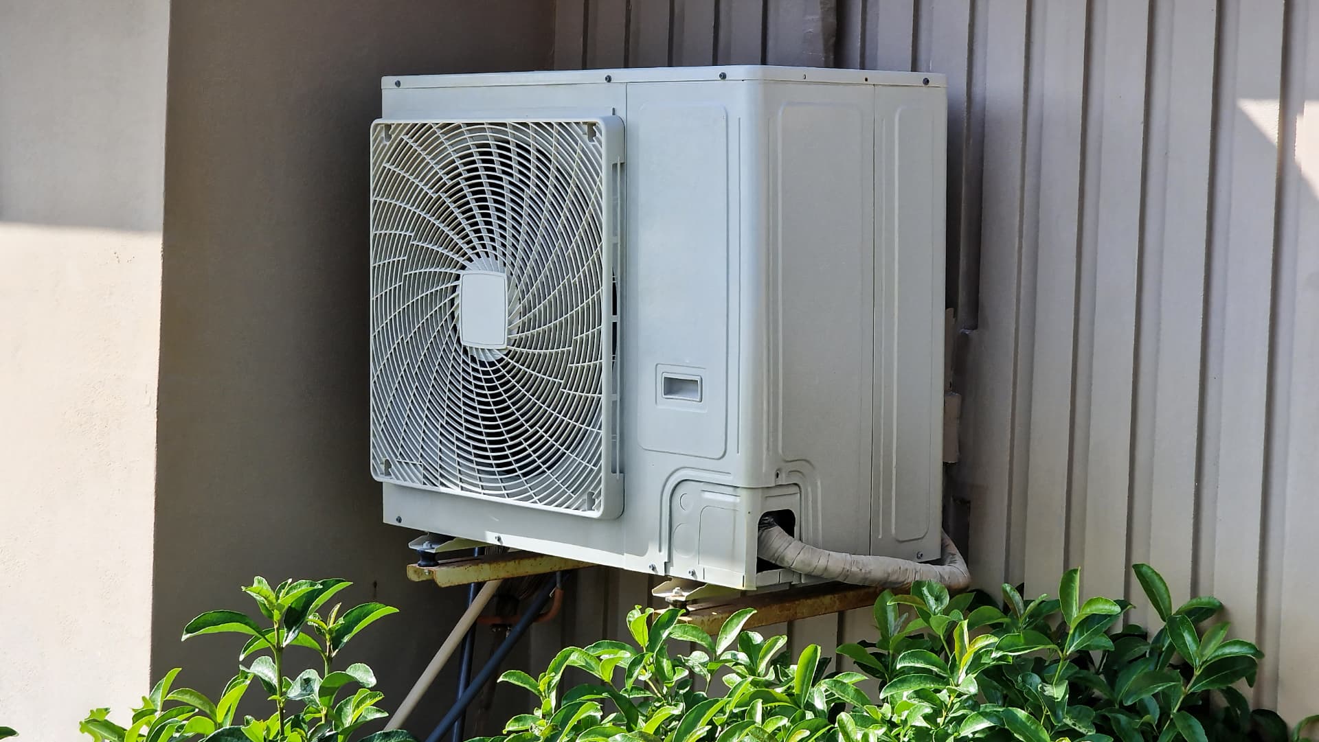 Outdoor ductless mini split condenser unit mounted on a home exterior wall