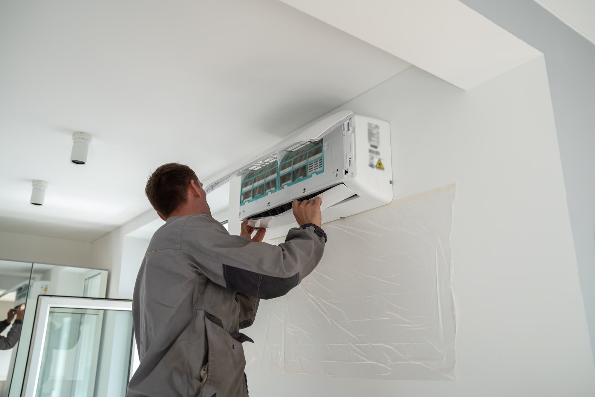 HVAC technician installing a ductless mini split indoor unit in a home